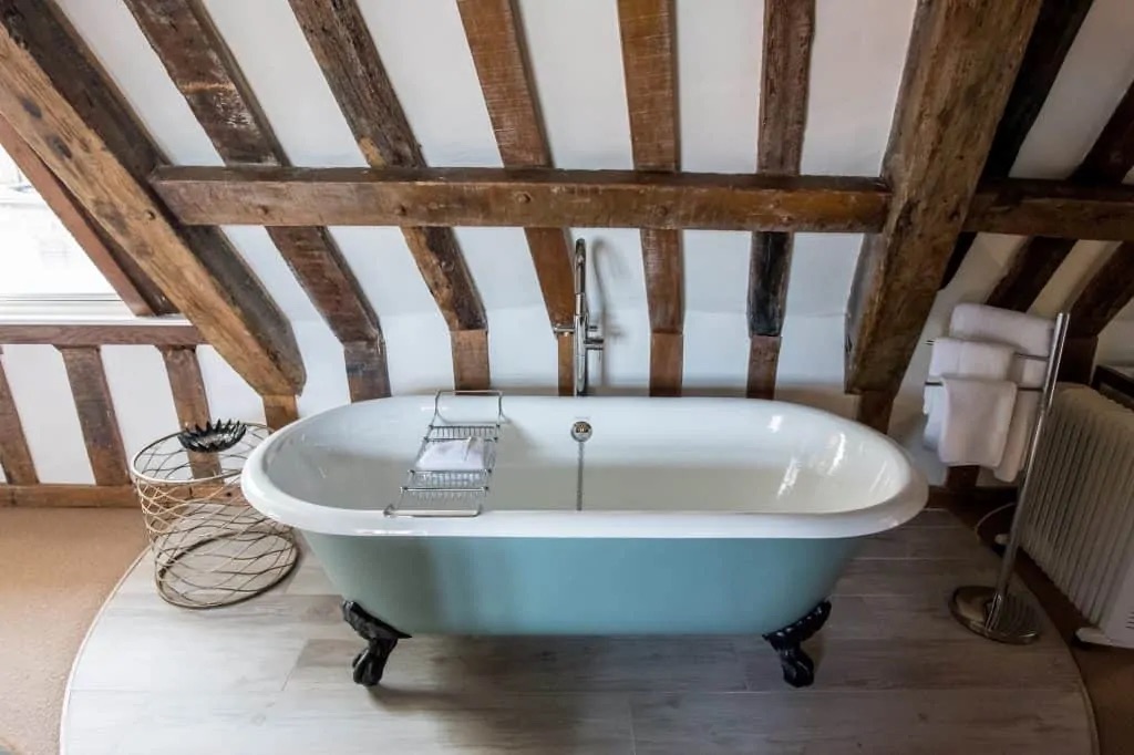 A pale blue roll-top bath under exposed beams