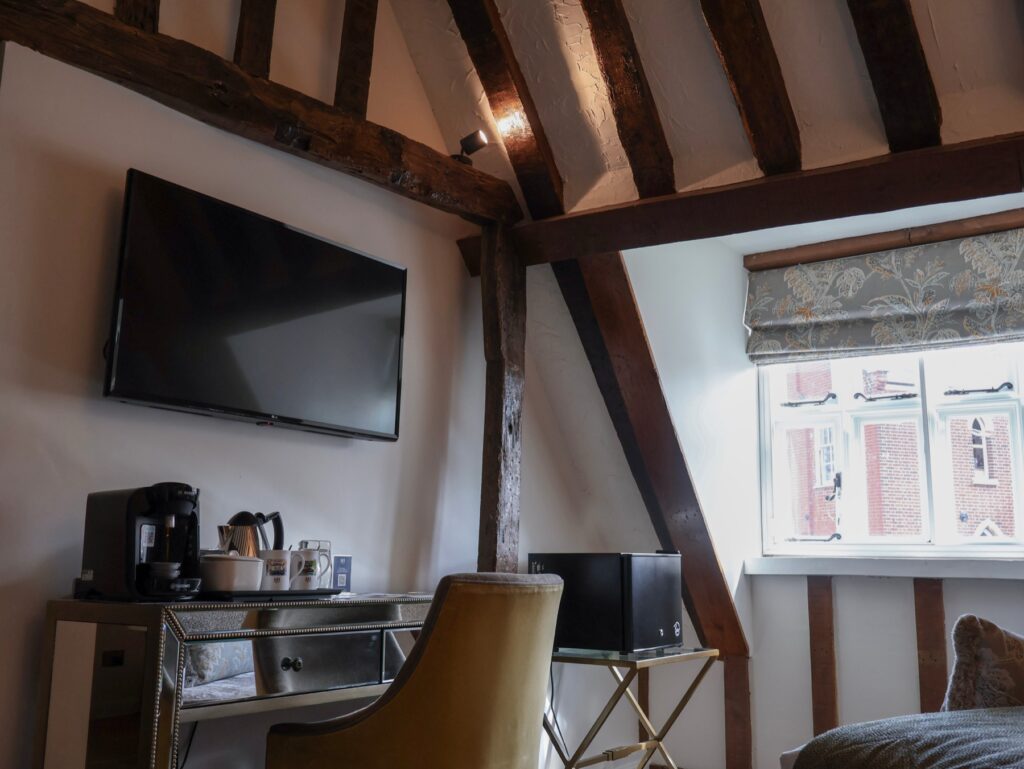 A desk and television under the sloping beamed ceiling
